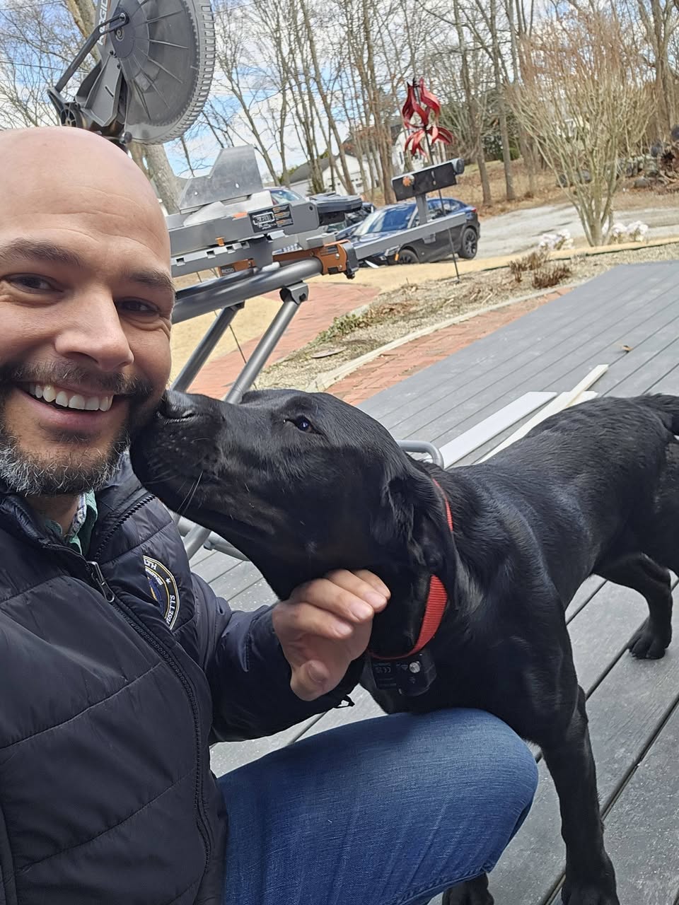 Joe McKenna getting a kiss from a black lab